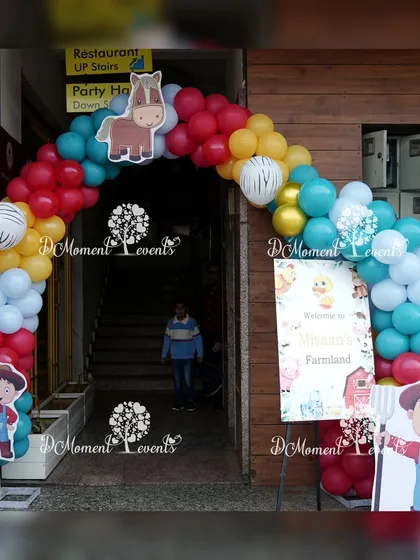 A colorful balloon arch with a horse cutout and farmer props creates a fun and welcoming entrance to the farmland party.