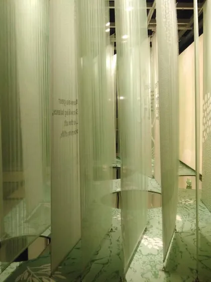 Our 'Cherish' installation, which uses layers of light green fabric to simulate the experience of forest bathing. Mirrored pools on the floor create reflections, adding to the sense of a tranquil, layered world.