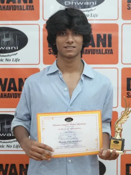 A student proudly displays his certificate and trophy for his artwork.
