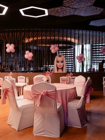 The dining setup for a Barbie party. I used pink table linens and chair sashes, with simple balloon clusters and a Barbie head centerpiece to continue the theme throughout the venue.