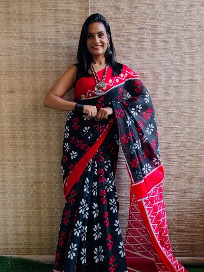 This black cotton Mulmul saree with red and white floral prints is a striking and beautiful piece. The color combination is bold and very attractive.