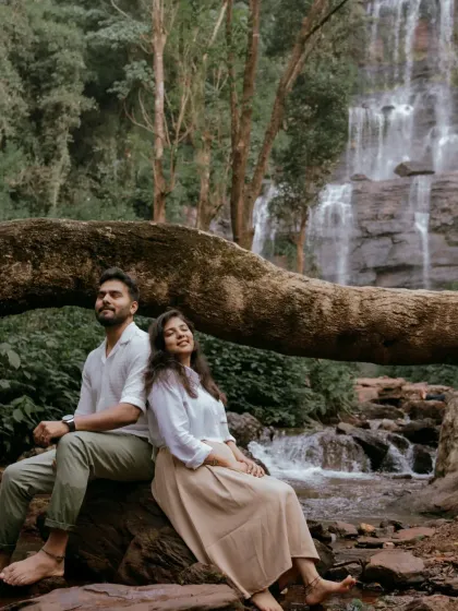 A relaxed pose on a fallen log in front of a waterfall. This image feels natural and comfortable, capturing a moment of rest during an adventurous shoot.