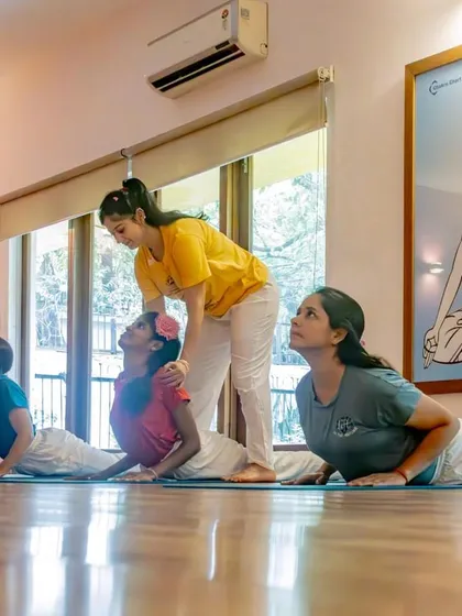 Here, one of our instructors provides gentle, hands-on assistance to young students in Bhujangasana, or Cobra Pose. We focus on correct alignment and individual attention to ensure a safe and effective practice for children.