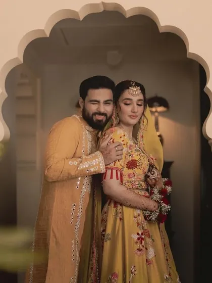 A playful moment between the couple, showcasing their coordinated Haldi outfits against a beautiful architectural backdrop.