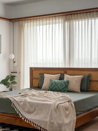 A closer look at the custom bed in the 'Vasudhalayah' master suite, featuring an elegant cane headboard and an earthy green color palette.