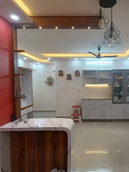 An open-plan living and kitchen area unified by a sophisticated false ceiling with perimeter cove lighting. This technique makes the space feel larger and brighter, highlighting the room's architecture.