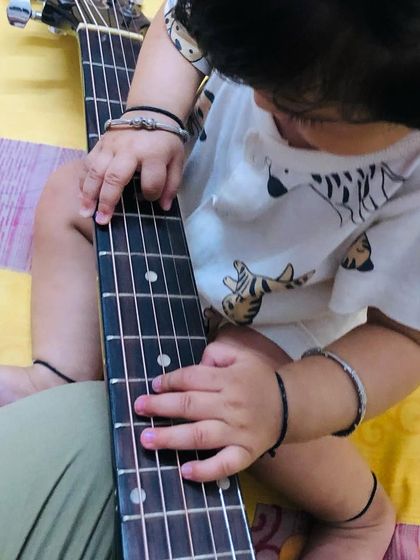 We believe in exposing children to music, not screens. A toddler's hands on a guitar represent the beginning of a lifelong love for music, which we encourage from the earliest age.