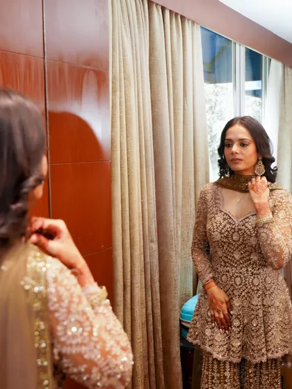 A candid moment of the bride getting ready. This reflection shot shows the complete look, with soft glam makeup that enhances her features beautifully for her special day.