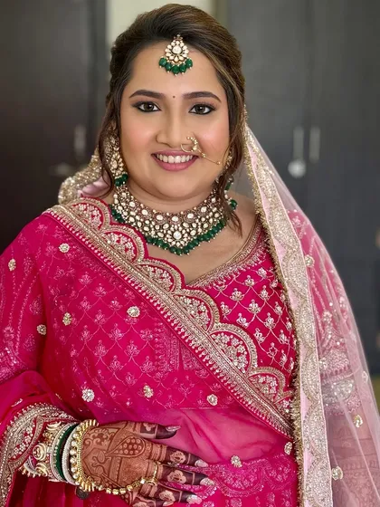 A full view of the bride's stunning pink lehenga and the beautiful details of her look. The makeup is balanced to feel both traditional and fresh.