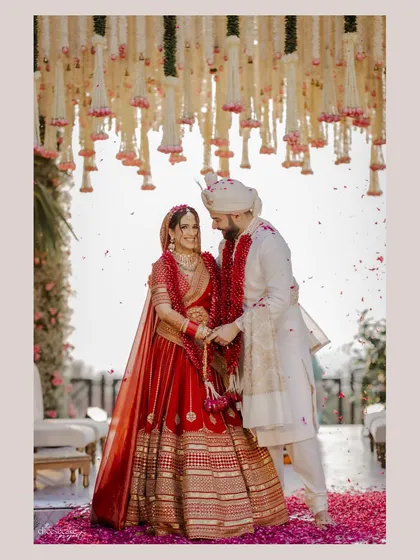 The couple's varmala moment, framed by the lush floral mandap. The design creates a perfect backdrop for iconic wedding photographs.