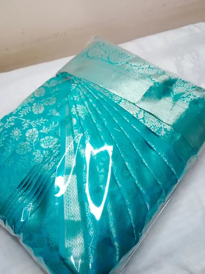 This turquoise saree is sealed and ready, ensuring the pleats remain perfect during transport.