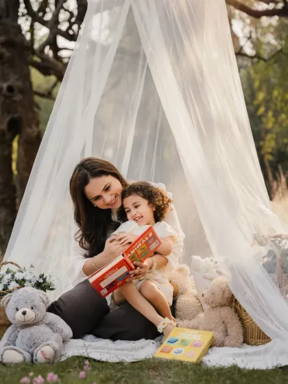 A mother reads a book to her daughter in their cozy outdoor teepee. A perfect way to capture a shared love of stories.