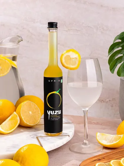 Showcasing Sprig's Yuzu Citrus Extract in a bright and refreshing setting. Surrounded by fresh lemons and a pitcher of water, this image communicates the product's natural flavor and its use in creating delicious drinks.