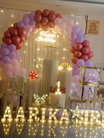 For this first birthday, I created a beautiful backdrop using a full balloon arch against a curtain of fairy lights. The design includes marquee letters and number, 'BABY' blocks, and other small props for a complete look.