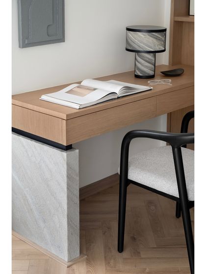 A close-up of the bespoke wooden study table in the master suite. The caldera stone leg is a unique, custom detail that elevates the design and demonstrates a sophisticated use of natural materials.