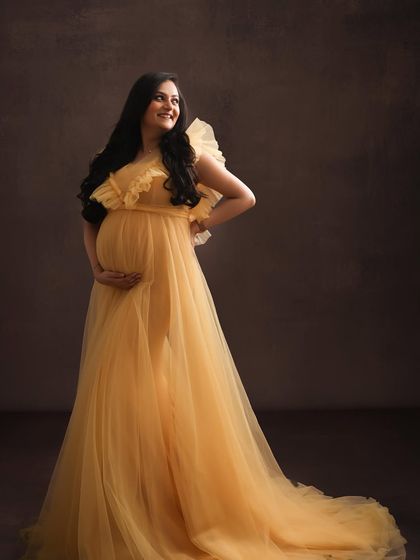 Bathed in a golden glow. This beautiful yellow tulle gown perfectly captures the warmth and happiness of pregnancy, creating a bright and joyful portrait.
