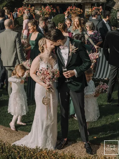 A beautiful kiss shared by the newlyweds, surrounded by the happy faces of their friends and family at their Cotswolds wedding. This shot captures the pure, celebratory energy of the moment.