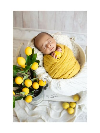 A single perfect shot from our lemon-themed session. The baby is wrapped snugly in yellow, surrounded by fresh lemons, creating a vibrant and cheerful portrait.