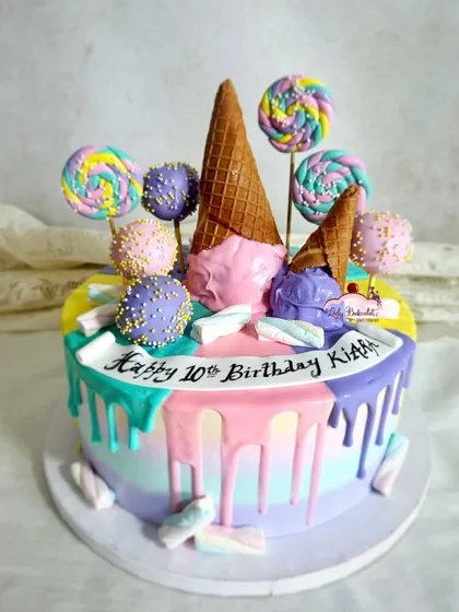 Another fun take on a Candyland theme, this cake uses a rainbow of pastel colors in a drip effect. It's topped with ice cream cones, lollipops, and cake pops for a playful and delicious tenth birthday celebration.