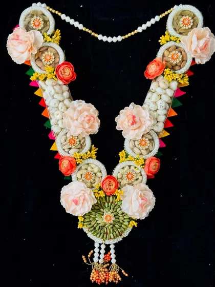 This edible garland is a work of art, featuring sections of dry fruits and decorated with beautiful handmade flowers.