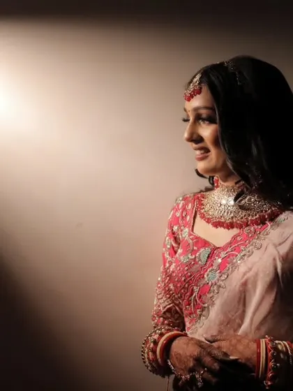 A dramatic portrait of a Marwari bride. The play of light and shadow highlights her features and the rich details of her red and pink lehenga.