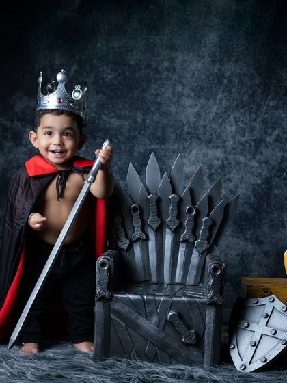 This little king is all smiles, proudly holding his sword on the Iron Throne.
