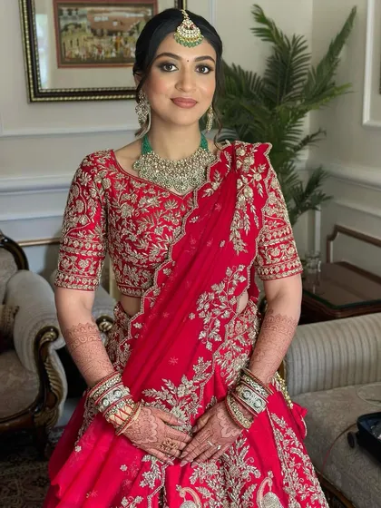 A full portrait of the bride in her traditional red lehenga. The makeup is designed to be timeless, with a modern edge that still feels classic.