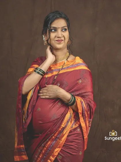 A candid, happy portrait of a mom-to-be in a traditional Maharashtrian saree, capturing a moment of pure joy.