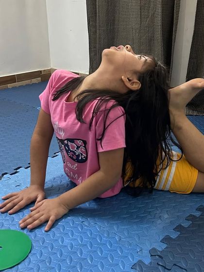 This young dancer is mastering the one-legged king pigeon pose, a deep stretch that improves flexibility in the hips and spine.