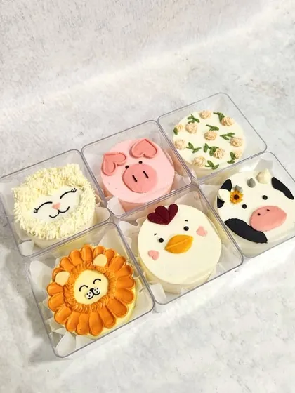 A cute set of six animal-themed mini bento cakes, including a lion, a pig, a chicken, and a cow.