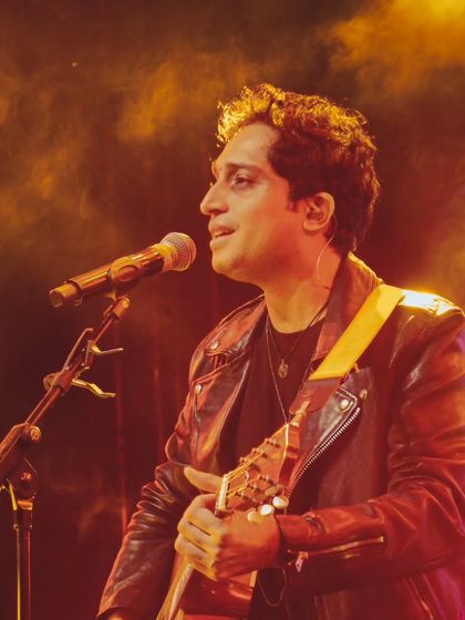 A close-up, atmospheric shot of Nikhil D'Souza performing under warm stage lights.