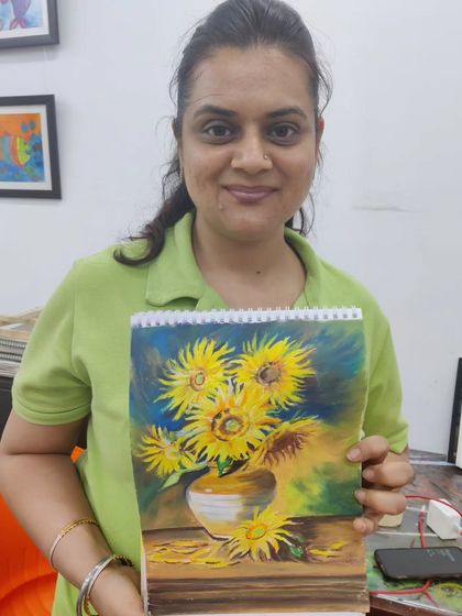 A student proudly displays her oil pastel artwork, a recreation of Van Gogh's "Sunflowers." We guide students in exploring the styles of master artists.