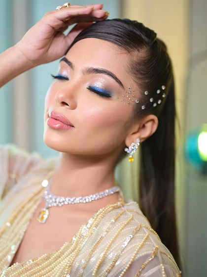 A super glam cocktail look with a pop of blue liner and scattered face crystals. This is a perfect example of combining classic glam with creative, modern elements.