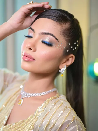 A super glam cocktail look with a pop of blue liner and scattered face crystals. This is a perfect example of combining classic glam with creative, modern elements.