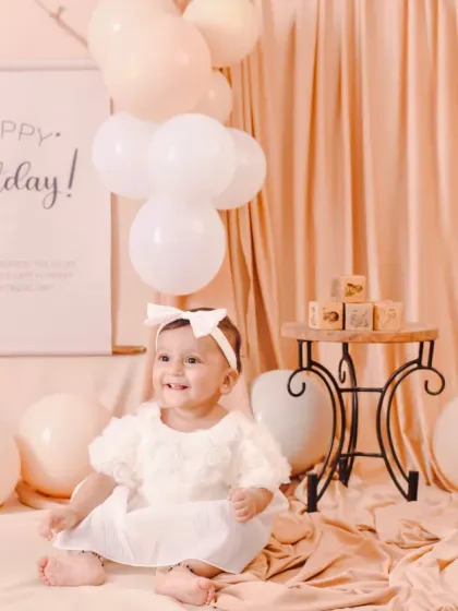 A happy smile from the birthday girl in a soft, neutral-toned setting. This classic and timeless setup is perfect for capturing their one-year milestone.