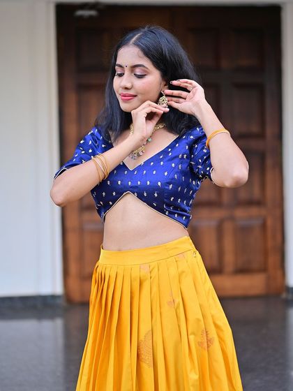 A model in a vibrant yellow and blue half-saree.