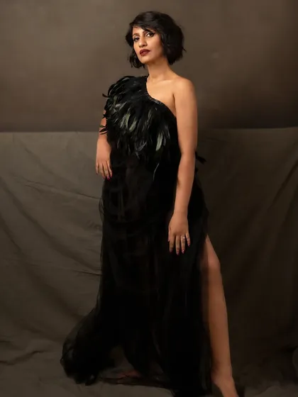 Dressed in a dramatic black feathered gown, she has an incredible, standout charisma. This portrait is both intimidating and exhilarating, capturing her unique and powerful presence.