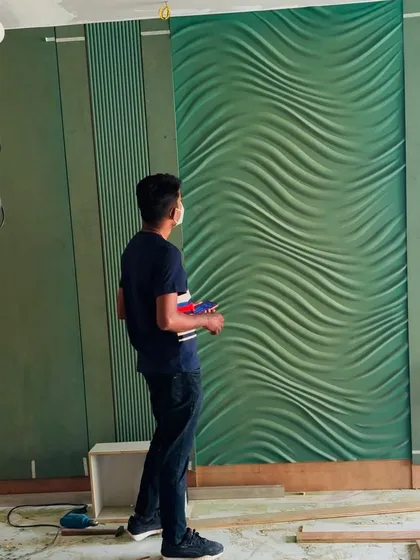A moment of admiration for a newly installed 3D wall panel in a striking green color.