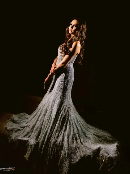 A full-length, dramatic portrait of the bride in her shimmering gown, the light catching the intricate details of her dress.