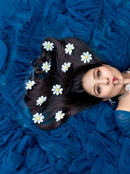 A playful and artistic overhead shot. The rich blue fabric provides a stunning contrast, while the flowers in her hair add a whimsical touch to this creative maternity portrait.