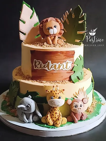 I love creating adorable jungle-themed cakes for little ones. This two-tiered chocolate cake features handmade, edible fondant animals like a lion, giraffe, and elephant, perfect for a wild first or second birthday party.