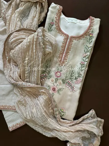 A full view of the suit, highlighting its soft color palette and intricate floral embroidery.