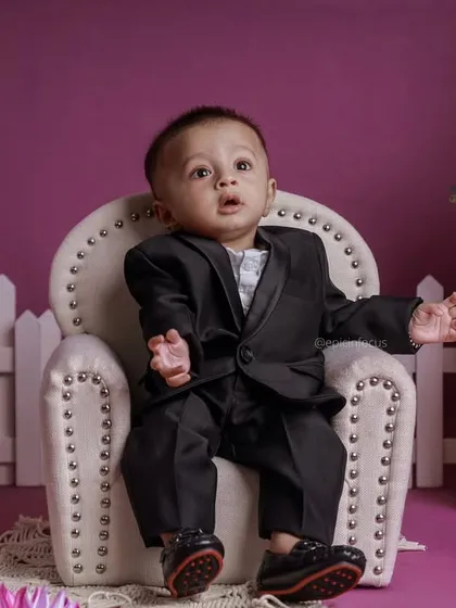 A handsome little man in a black suit sits against a lovely purple backdrop. Our simple color-themed shoots are perfect for classic, elegant portraits.