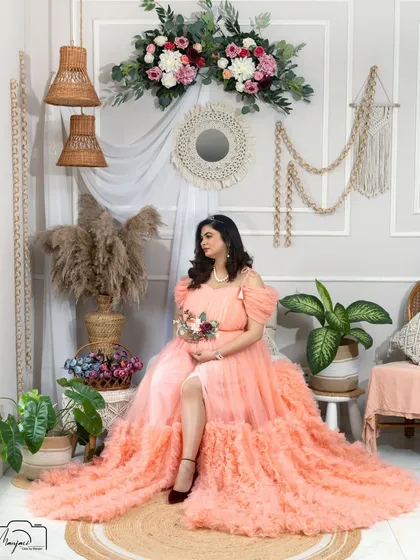 A beautiful full-length portrait of the mama-to-be, seated gracefully in the boho corner. The peach gown looks stunning against the natural textures.