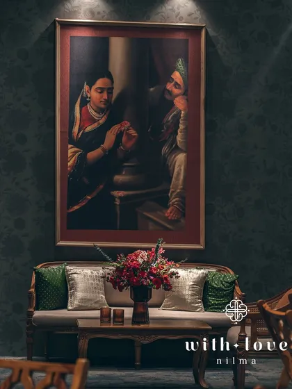 A seating arrangement featuring a classic sofa set against a wall adorned with a Raja Ravi Varma painting. The decor blends seamlessly with the art, creating a cohesive and immersive environment.