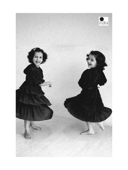 The joy of sisterhood. These twin girls are captured mid-twirl in a simple studio setting. The black and white treatment emphasizes their movement and the pure happiness on their faces.