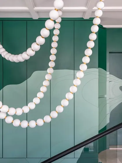 Another view of the stunning pearl necklace chandelier against the green paneled wall. This feature transforms the staircase area into a luxurious and memorable design moment.