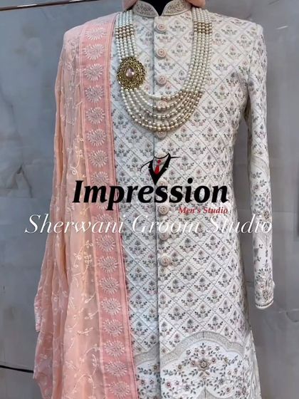 A beautifully styled white sherwani with subtle floral embroidery, paired with a soft peach stole. This look is perfect for a day wedding or a groom who prefers understated elegance.