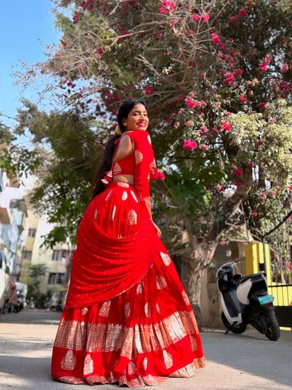 This vibrant red half saree is perfect for making a statement. The gold block prints on the skirt and the matching full-sleeve blouse create a look that is both traditional and bold.