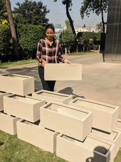 A team member holds up one of the rectangular FRP planters to show how light and manageable it is. This feature is a significant advantage during large-scale installations like this one.